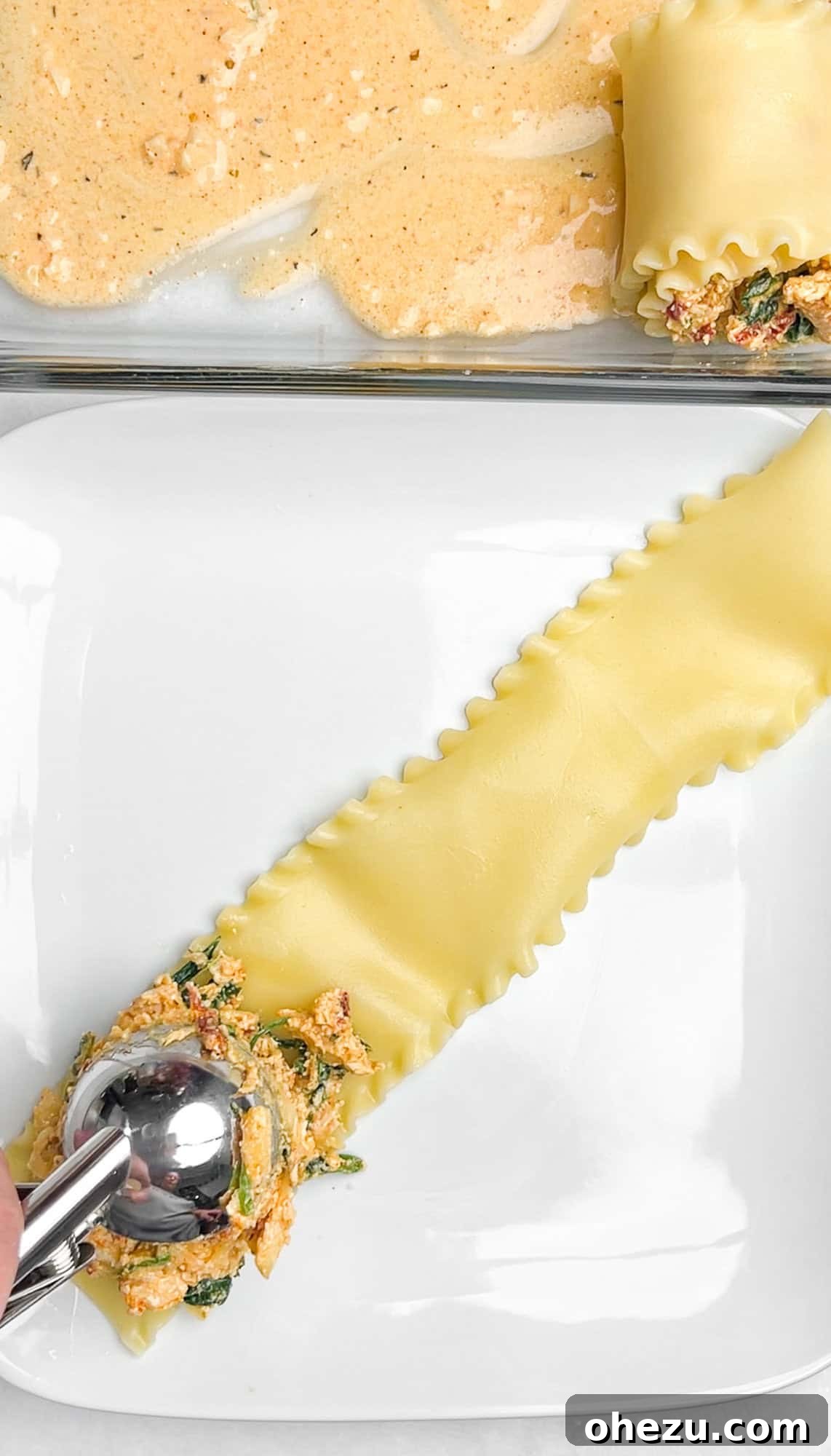 Spreading creamy filling evenly on a cooked lasagna noodle