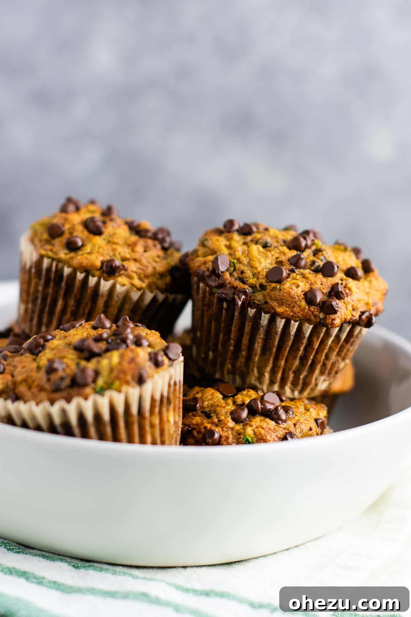 Close-up of freshly baked zucchini chocolate chip muffins on a cooling rack, showcasing the golden-brown tops and melted chocolate chips.