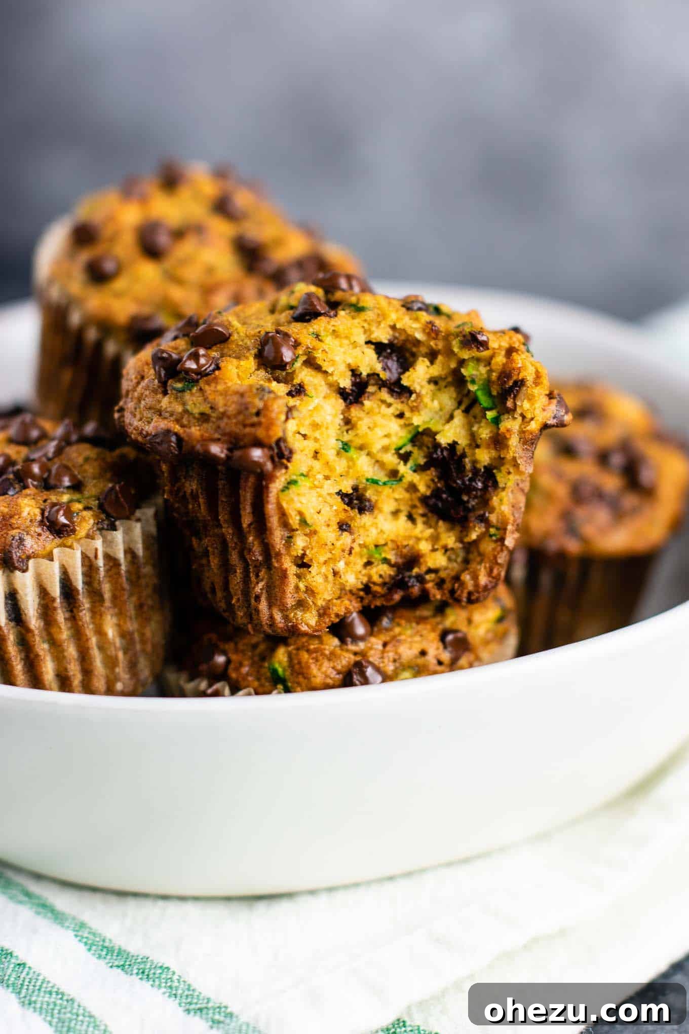 Freshly grated zucchini being pressed between paper towels to remove excess moisture, essential for moist muffins.