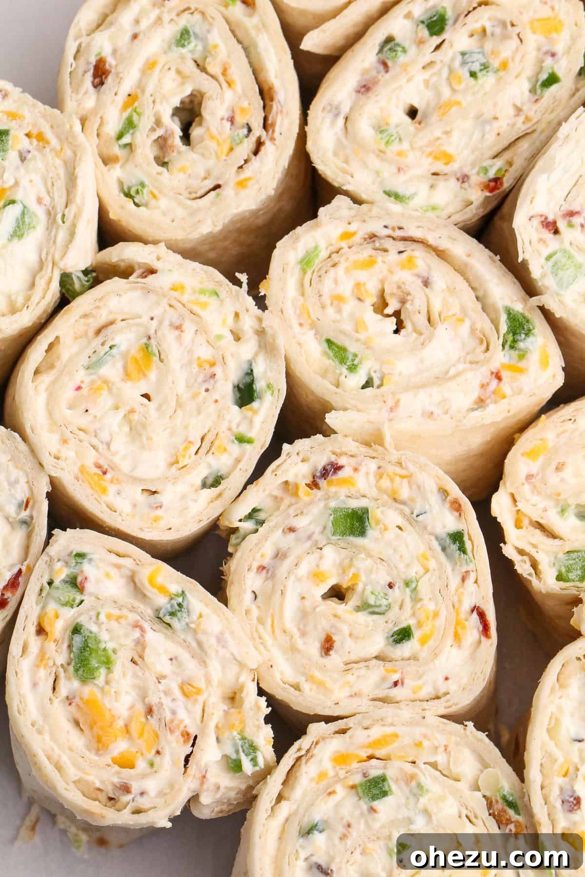 A selection of key ingredients for Jalapeno Popper Toasted Pinwheel Sandwiches including tortillas, cream cheese, jalapenos, and shredded cheese