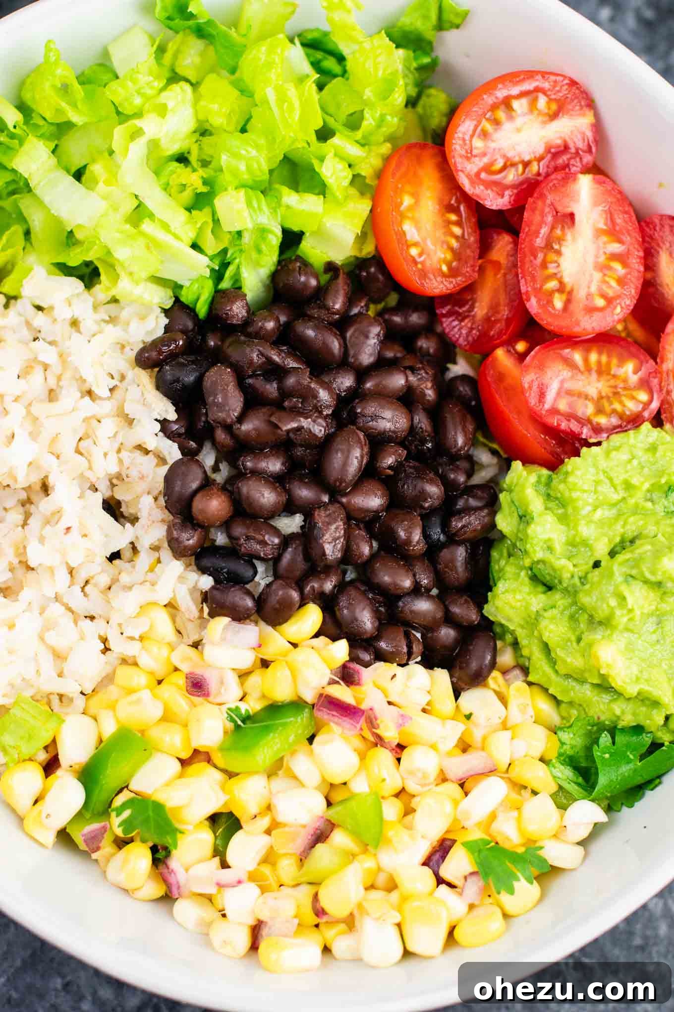 Ingredients for a vegan burrito bowl laid out, including a bowl of seasoned black beans, fresh lettuce, and cherry tomatoes. Perfect for healthy meal prep. #blackbeans #burritobowlingredients #simplevegan #healthyfood