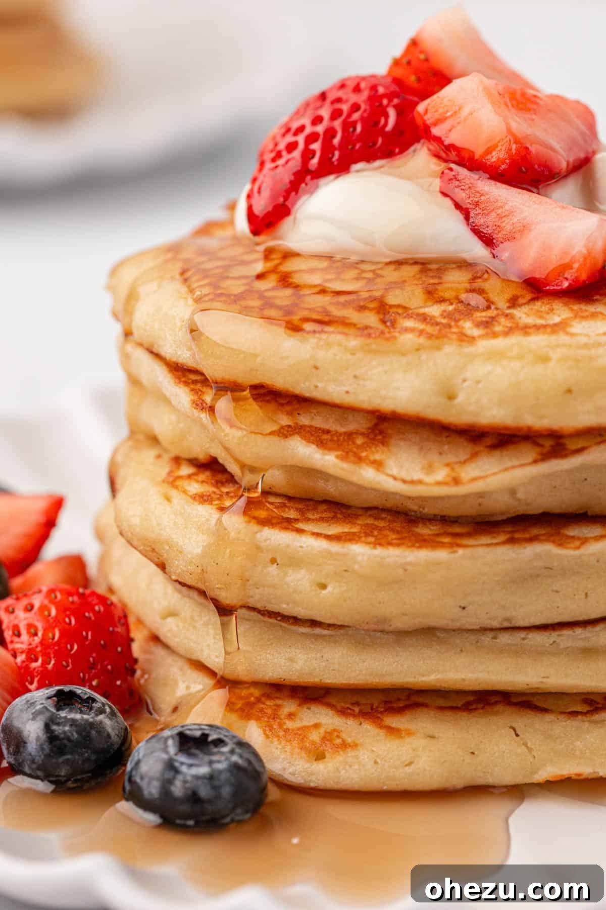 Stack of fluffy Greek yogurt pancakes drizzled with syrup and topped with fresh berries.
