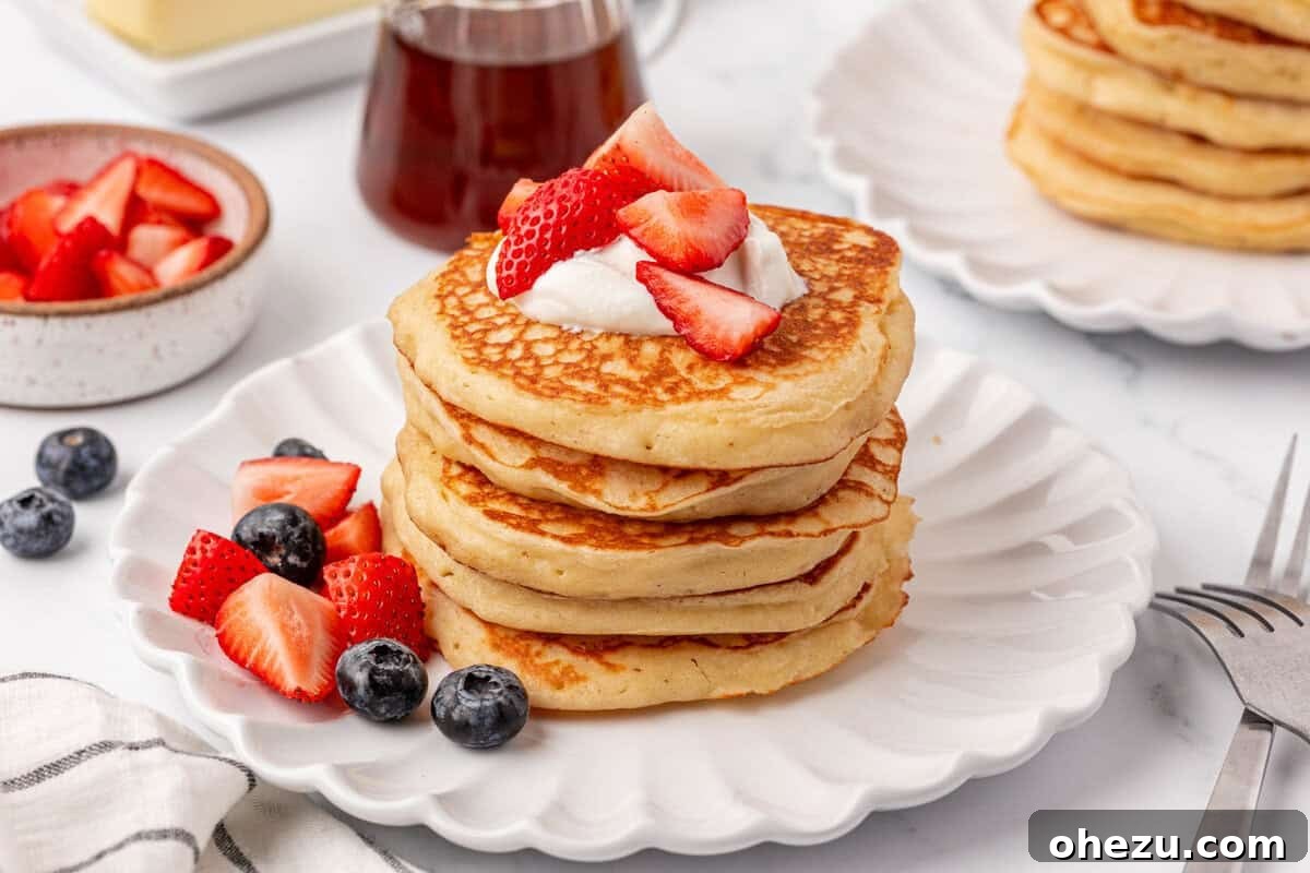 Greek yogurt pancakes topped with fresh strawberries, blueberries, and a drizzle of syrup.