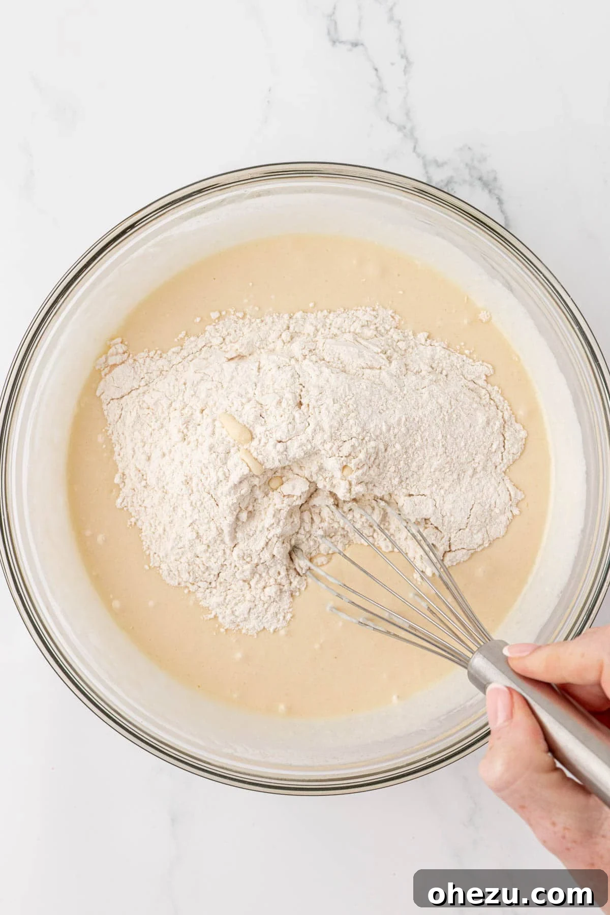 Adding dry ingredients mixture into the wet ingredients bowl.