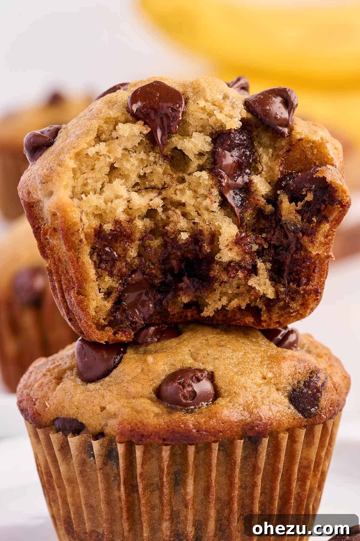 Moist Banana Greek Yogurt Muffins 18 Several Greek yogurt banana muffins arranged artfully on a light background, showcasing their golden tops and chocolate chips.