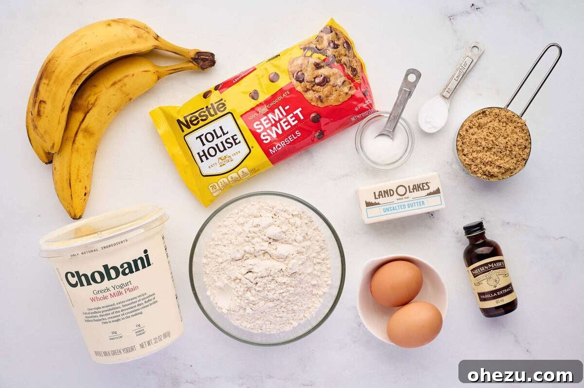 Moist Banana Greek Yogurt Muffins 4 A collection of fresh ingredients laid out on a kitchen counter, including ripe bananas, Greek yogurt, butter, flour, eggs, and chocolate chips, ready to make muffins.