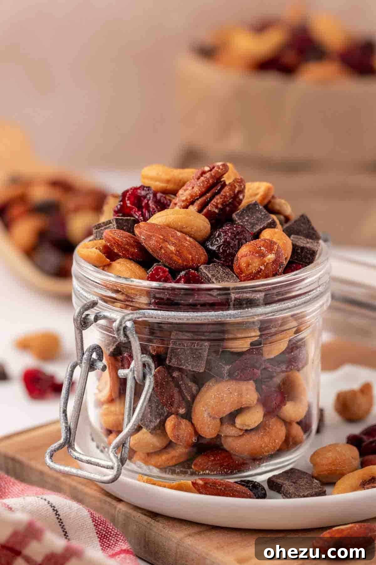 A glass jar filled with a delicious homemade trail mix, featuring mixed nuts, dark chocolate chunks, and dried cranberries, ready for snacking.