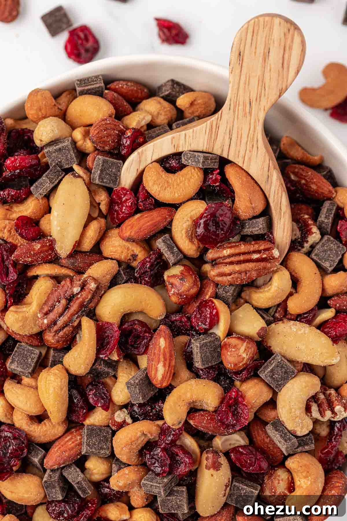 A close-up shot of homemade trail mix in a bowl, with a small metal scoop resting inside, emphasizing its readiness for serving and enjoyment.