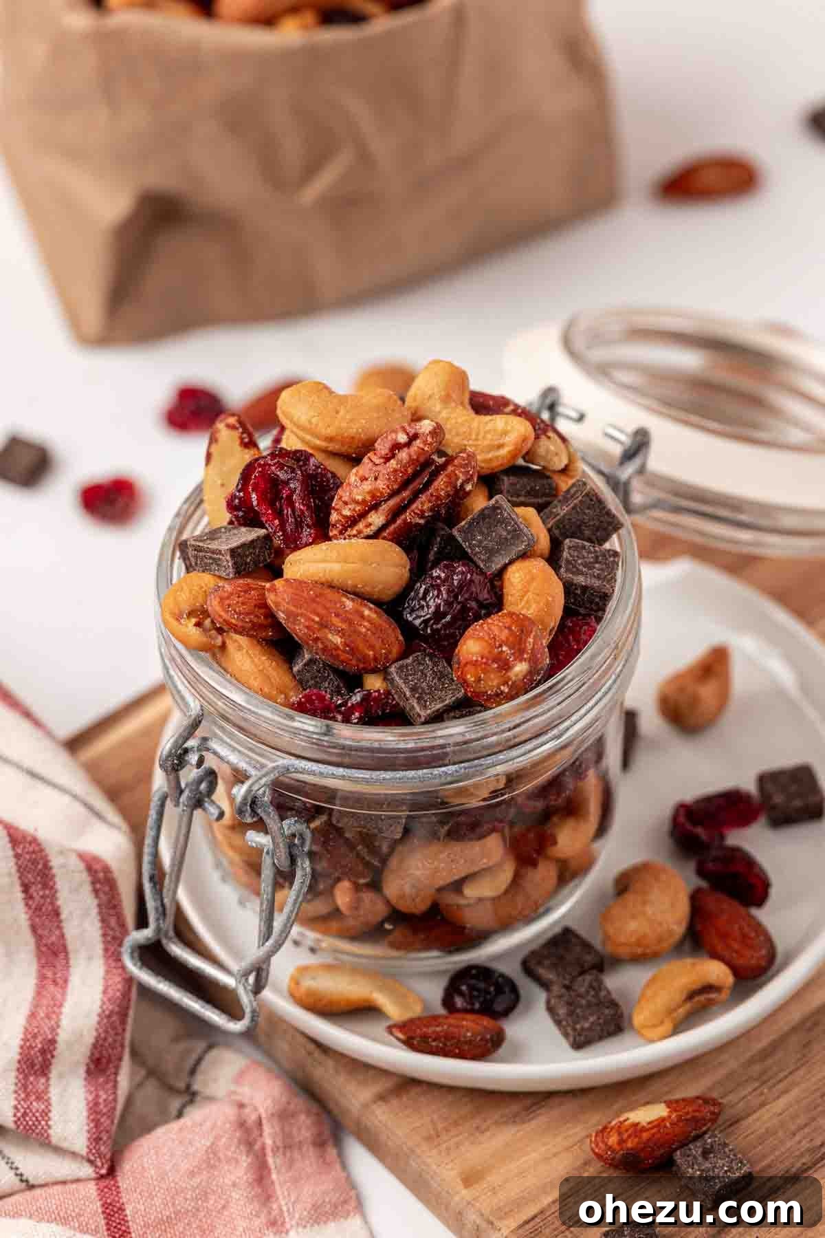 A close-up of a rustic glass jar filled with homemade trail mix, showing the vibrant mix of nuts, cranberries, and chocolate, ready for storage or gifting.