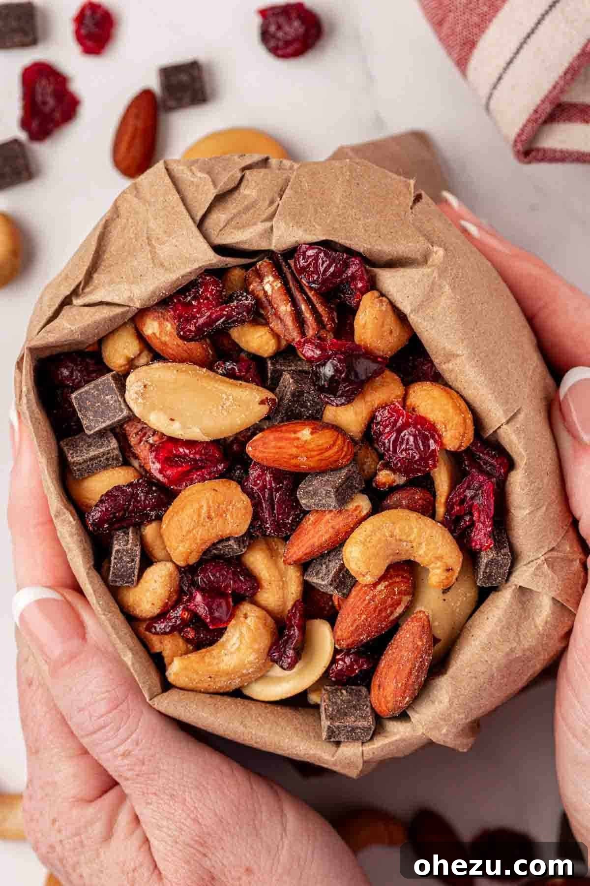 A small, neatly folded paper bag filled with homemade trail mix, placed on a wooden surface, emphasizing its simple and portable nature.