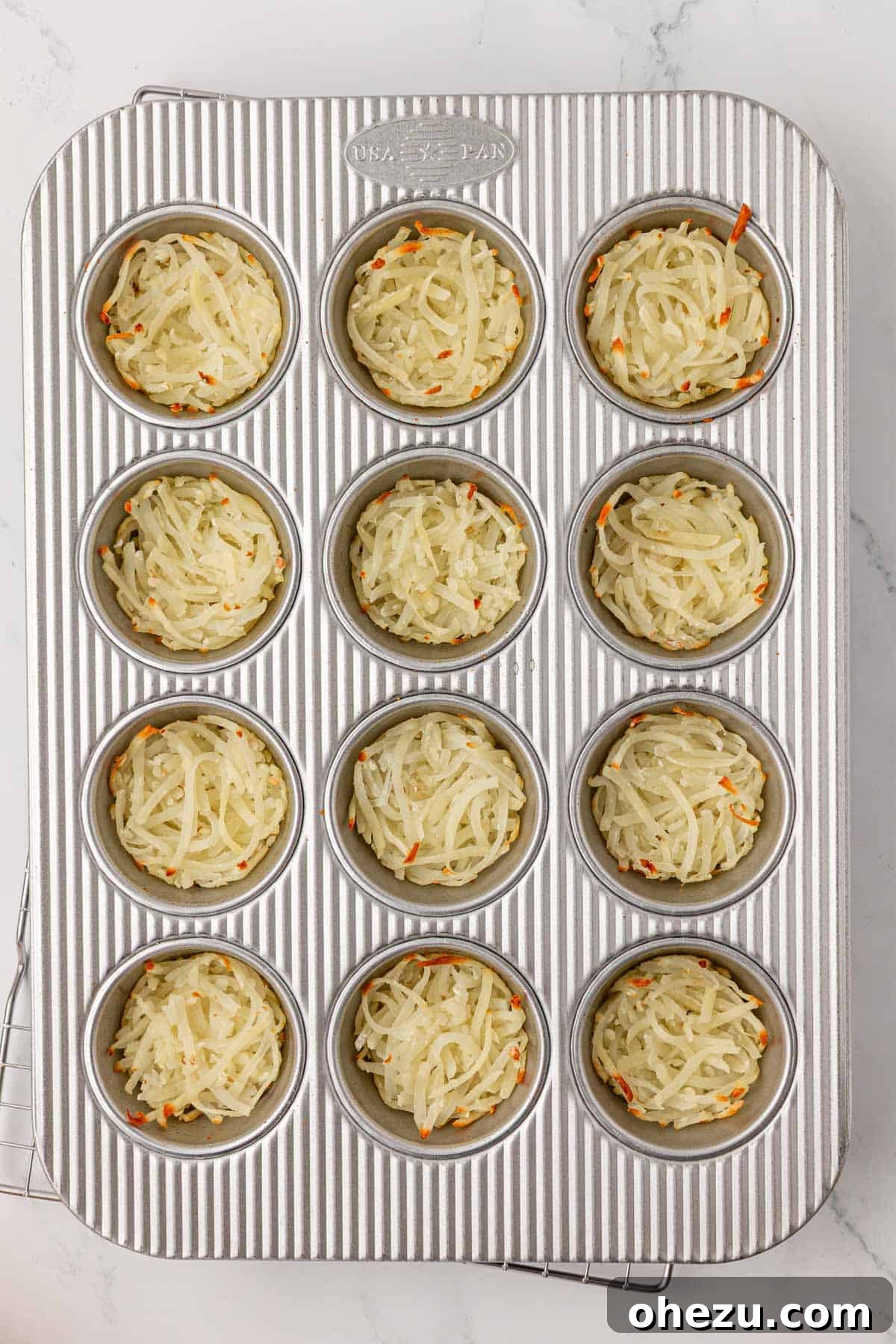 crispy hash browns in a muffin tin, ready for the egg mixture
