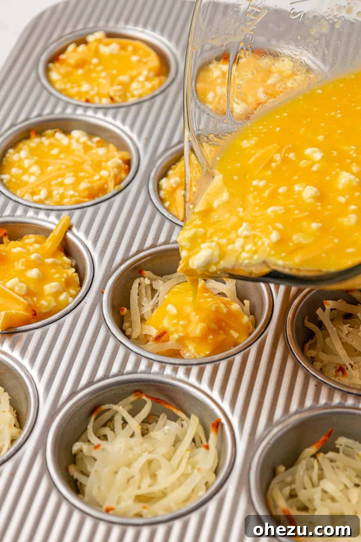 pouring egg filling evenly over the hash browns in the muffin tin