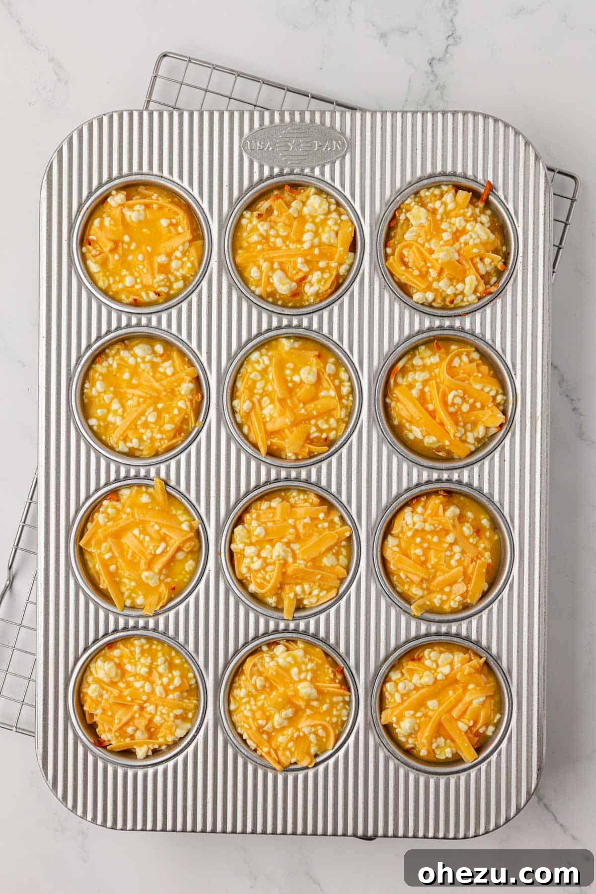 hash brown egg cups in the muffin tin just before baking with the egg mixture
