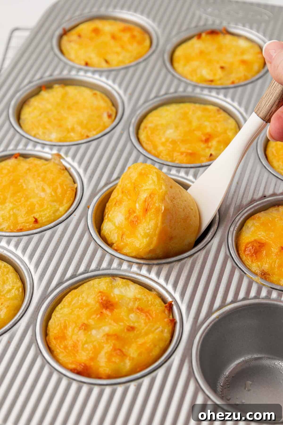 using a mini spatula to remove hash brown egg cups from the pan effortlessly