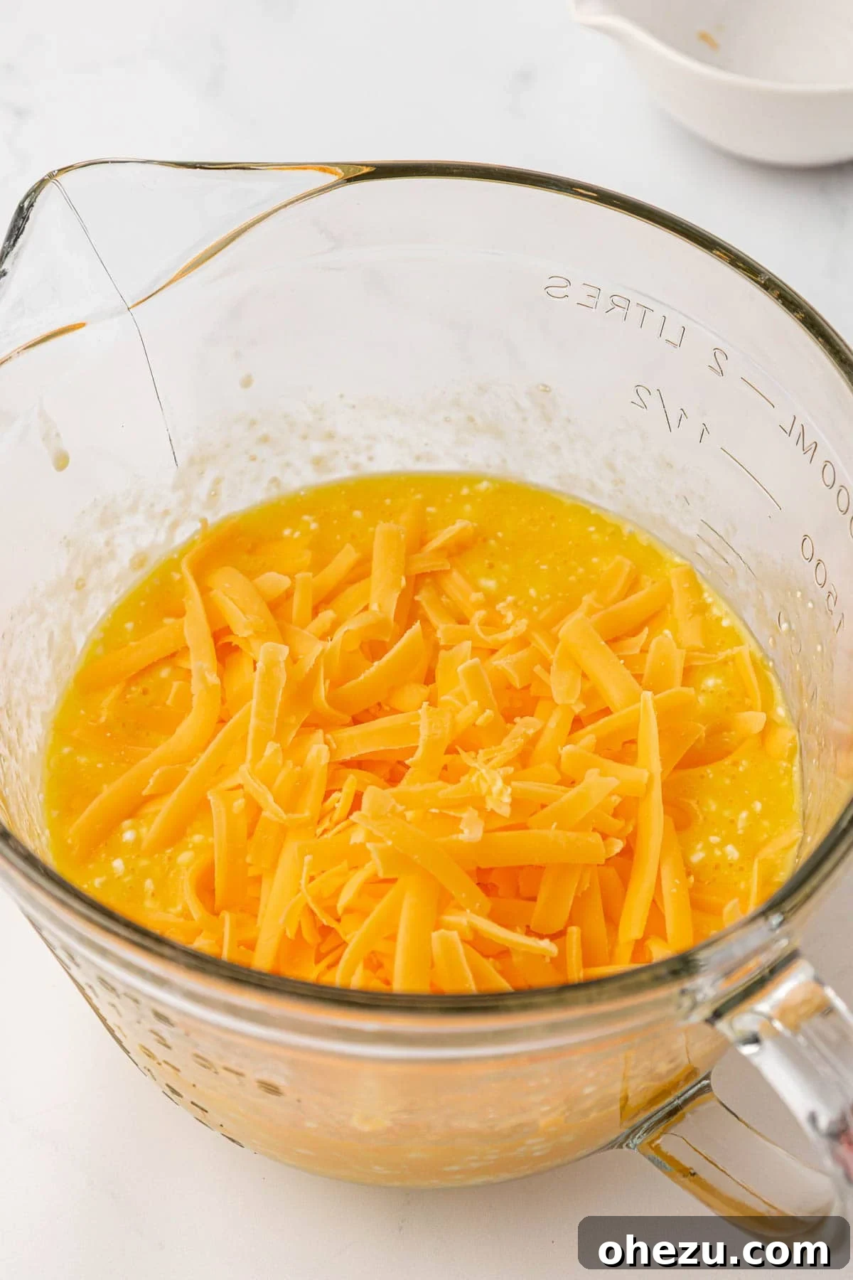 adding freshly grated cheese to the egg mixture