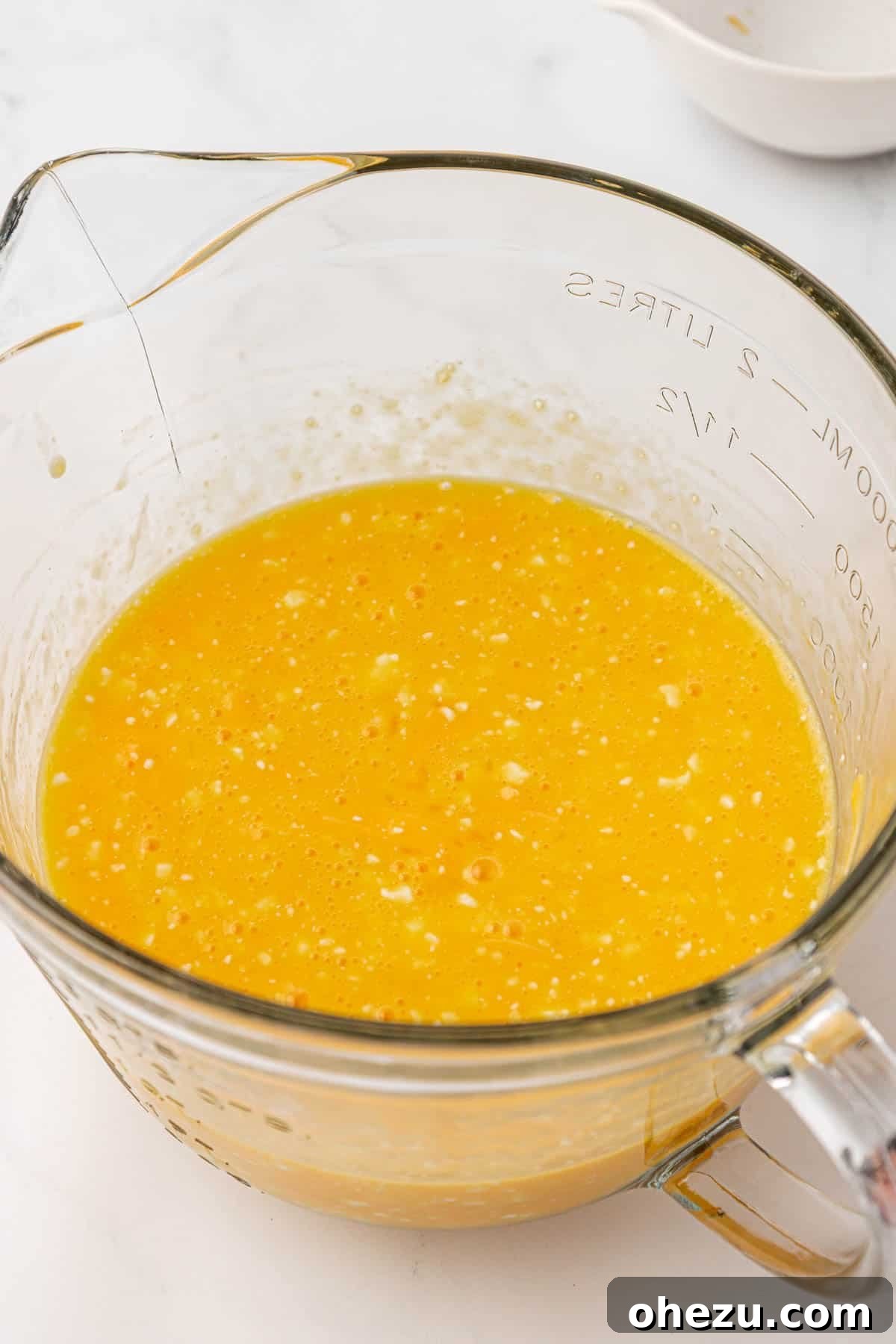 eggs whisked together with cottage cheese and cheddar in a measuring cup, ready to pour