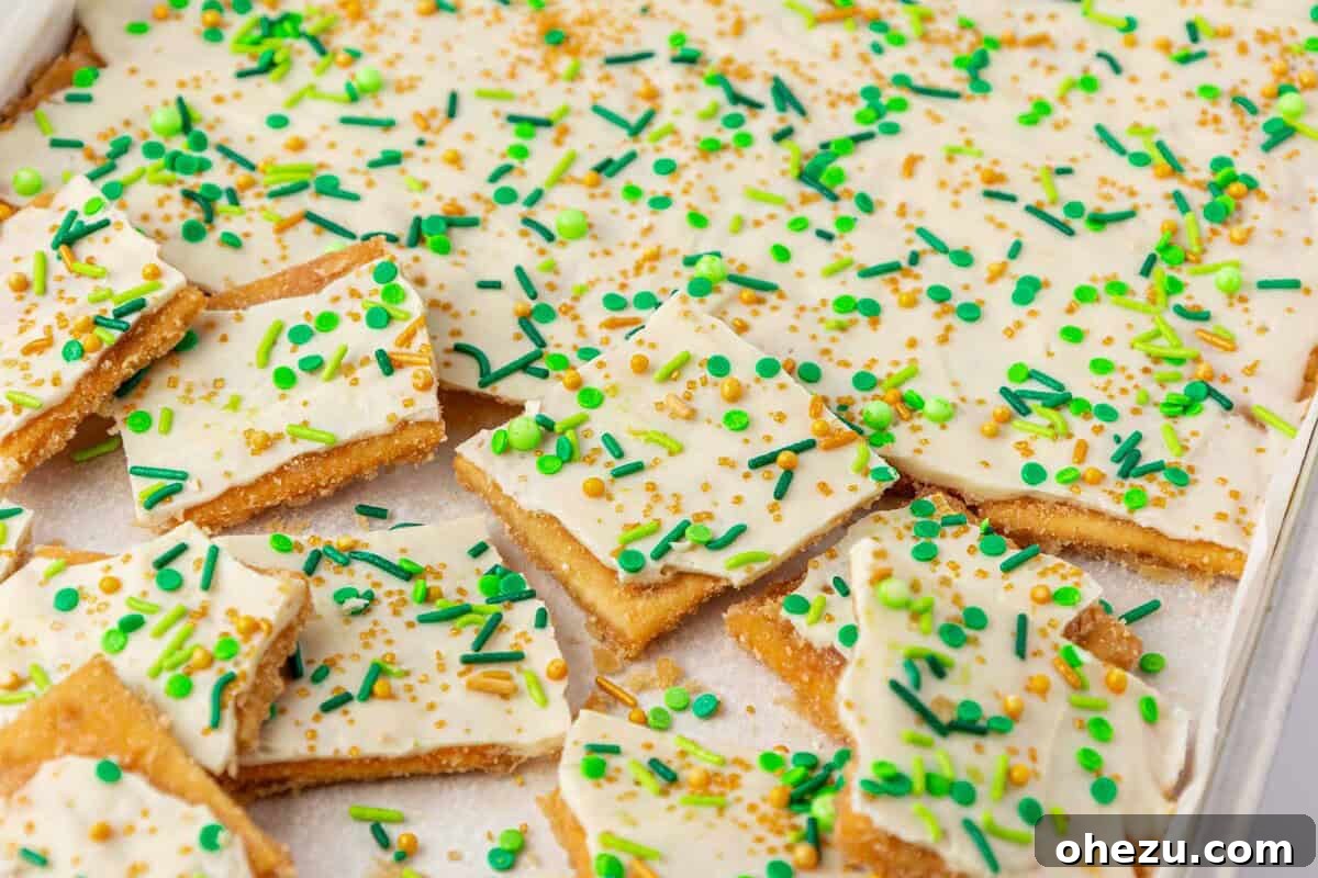 Leprechaun Crack: a vibrant St. Patrick's Day saltine toffee dessert topped with white chocolate and green and gold sprinkles.