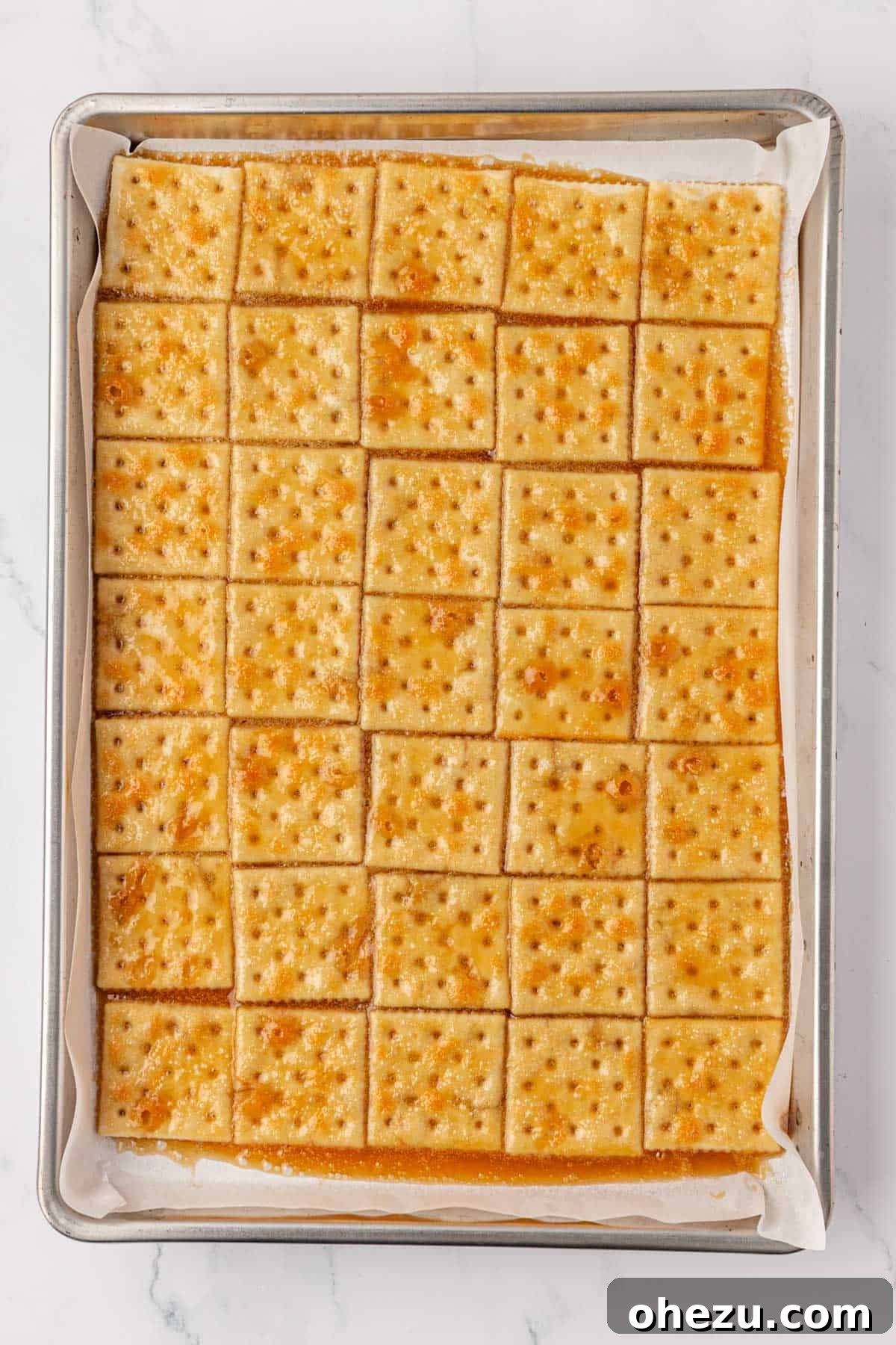 The baked toffee-covered saltines on a sheet pan, golden-brown and bubbly fresh from the oven.