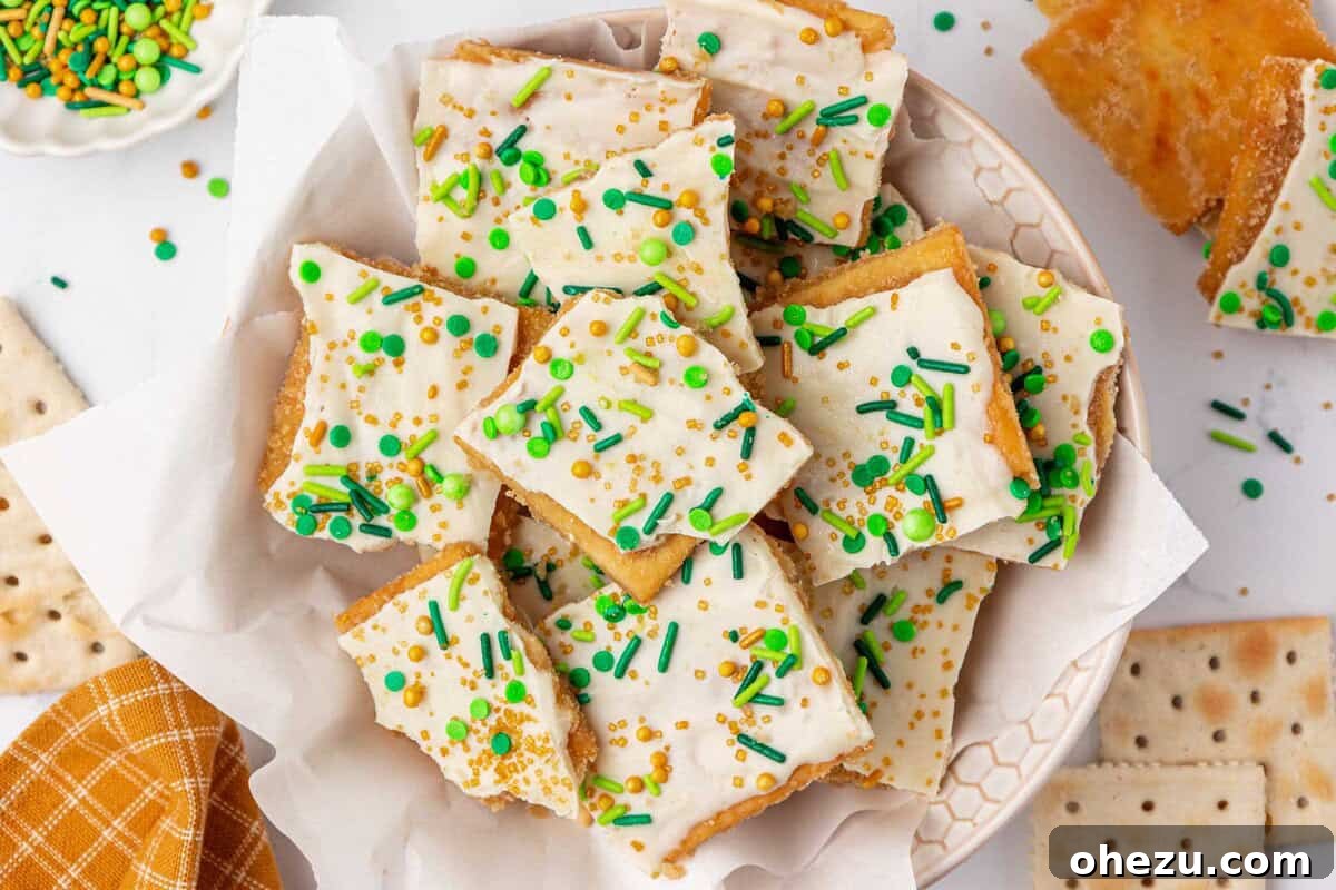 A beautifully presented serving of St. Patrick's Day saltine toffee with white chocolate and green and gold sprinkles on a white plate, ready to be enjoyed.