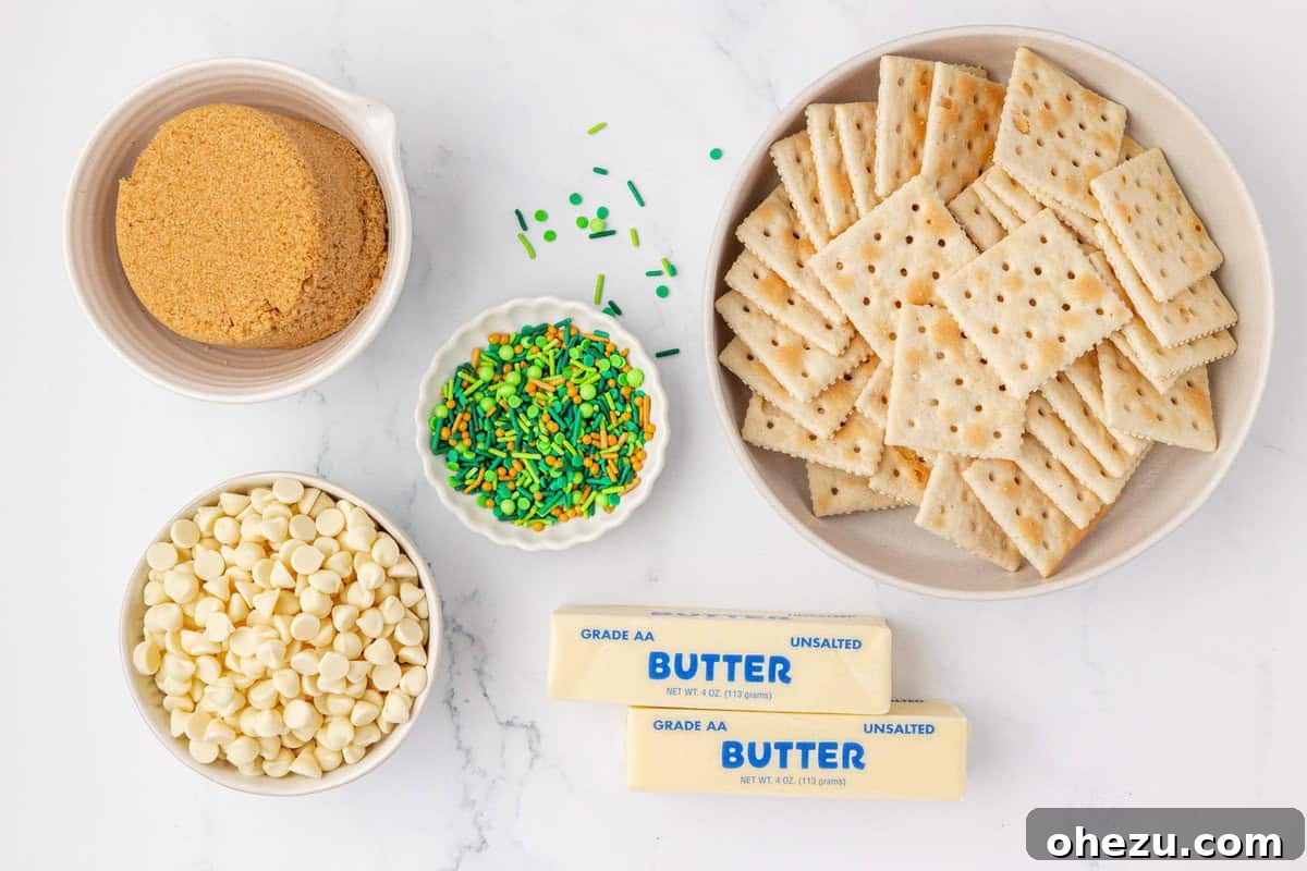 Assorted ingredients for Leprechaun Crack laid out: brown sugar, white chocolate chips, green and gold sprinkles, saltine crackers, and a stick of butter.