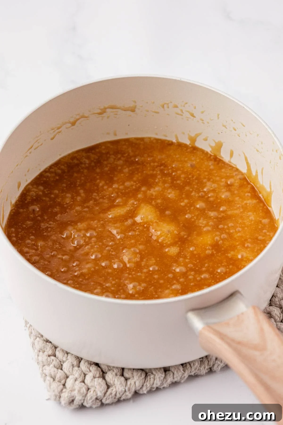 The butter and brown sugar mixture bubbling and thickening into a rich toffee in a saucepan.
