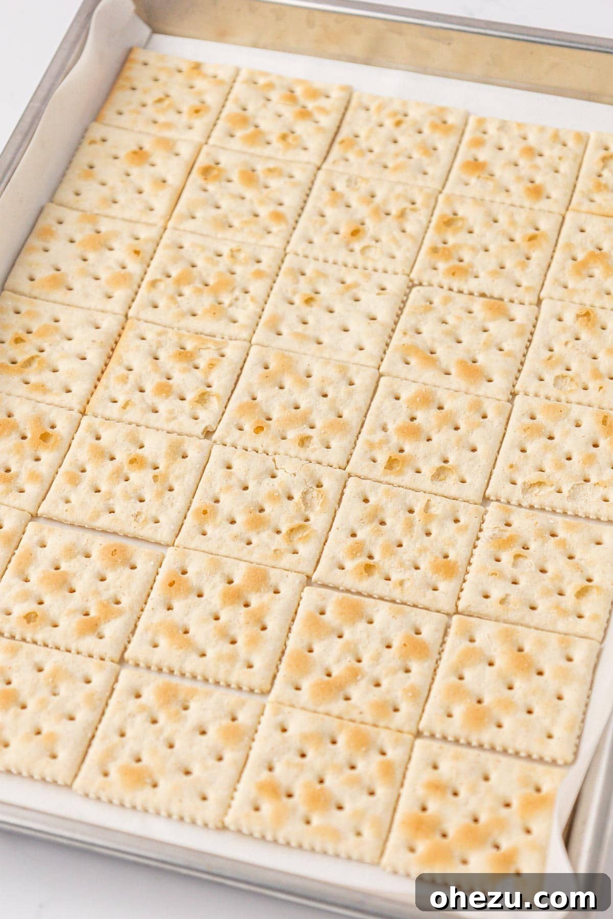 A baking sheet of saltine crackers awaiting the toffee coating.