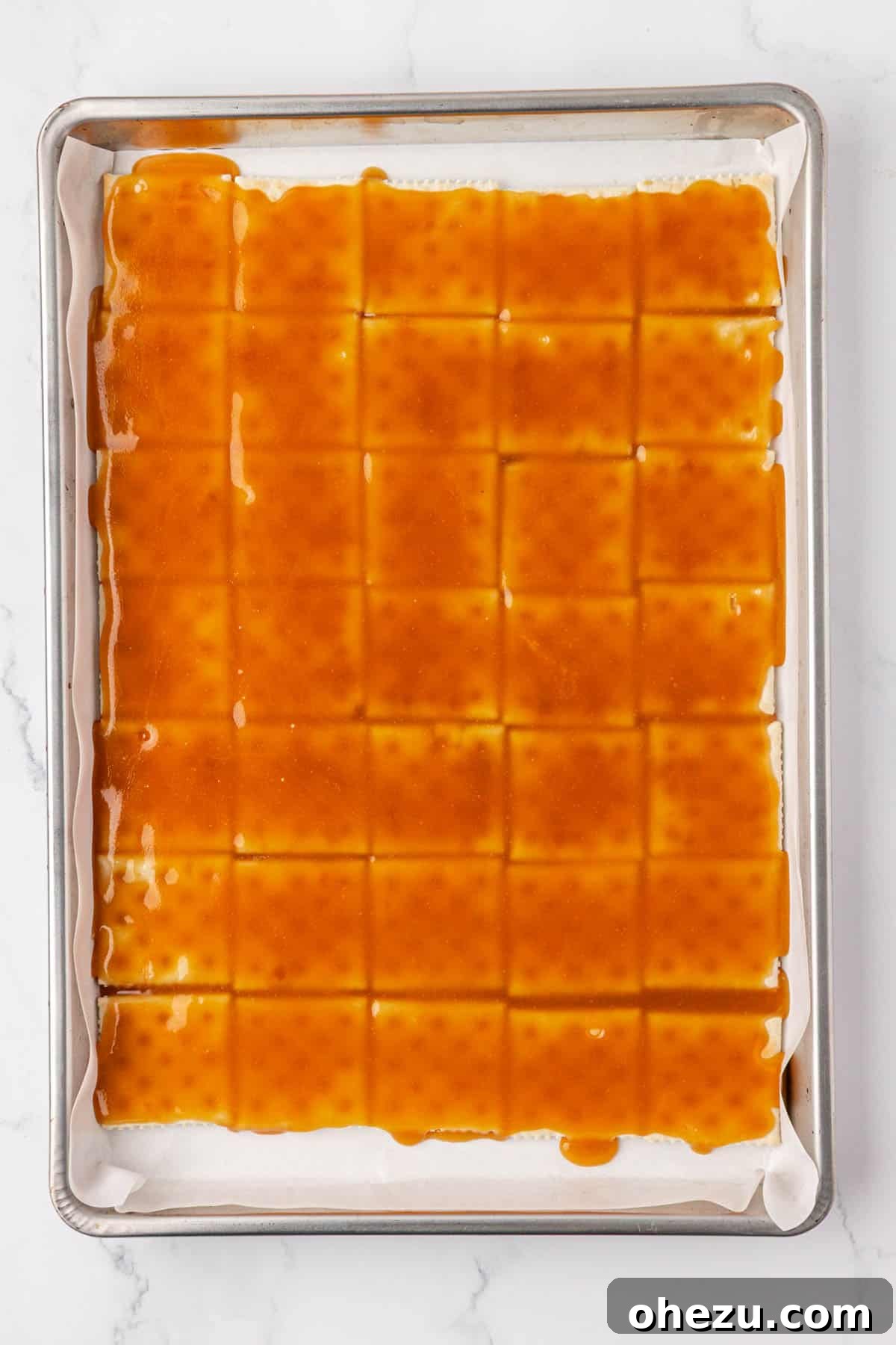 The toffee spread smoothly over the saltines on a baking sheet, ready for the oven.