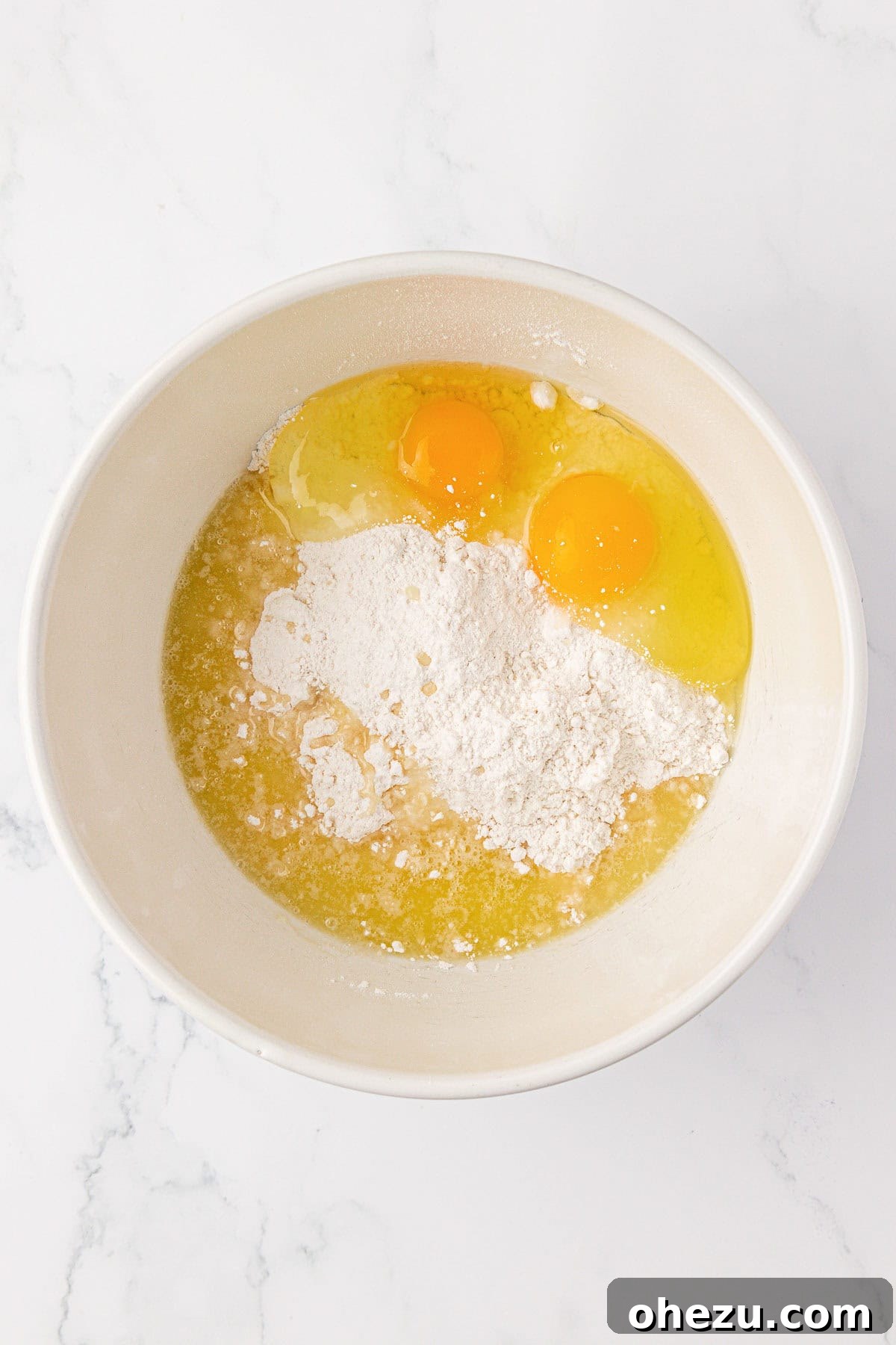 Eggs, cake mix, and melted butter being combined in a mixing bowl.