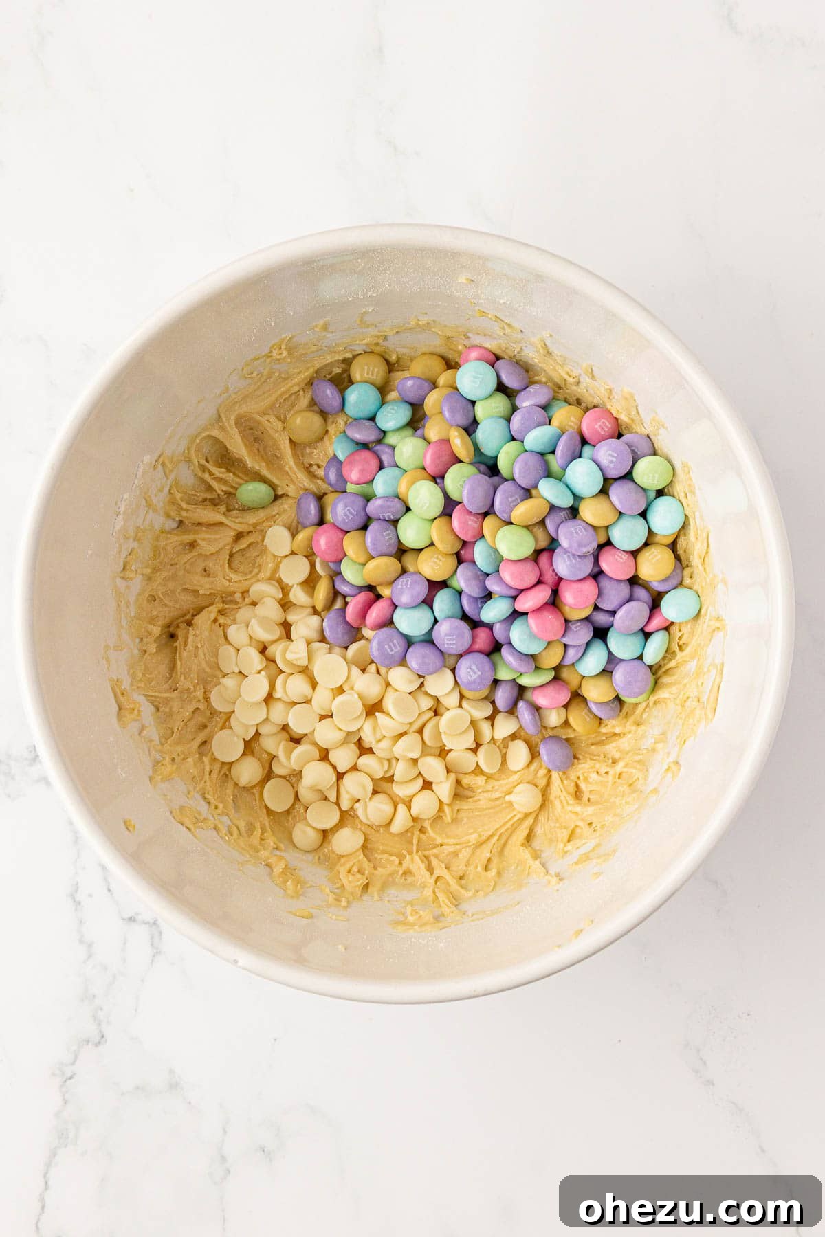 Adding white chocolate chips and M&M's to the cake mix batter.