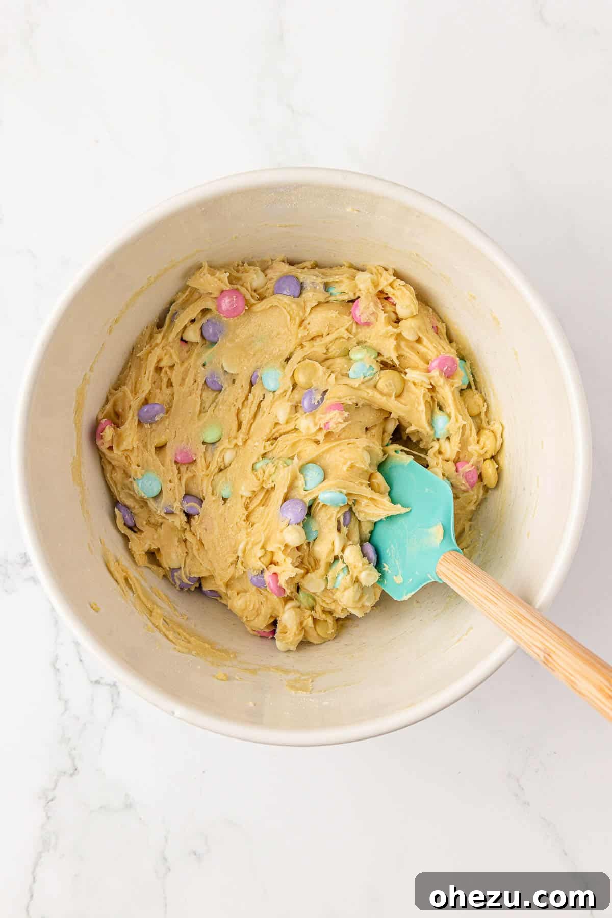 Easter cookie bar batter mixed with M&M's and chocolate chips in a bowl.