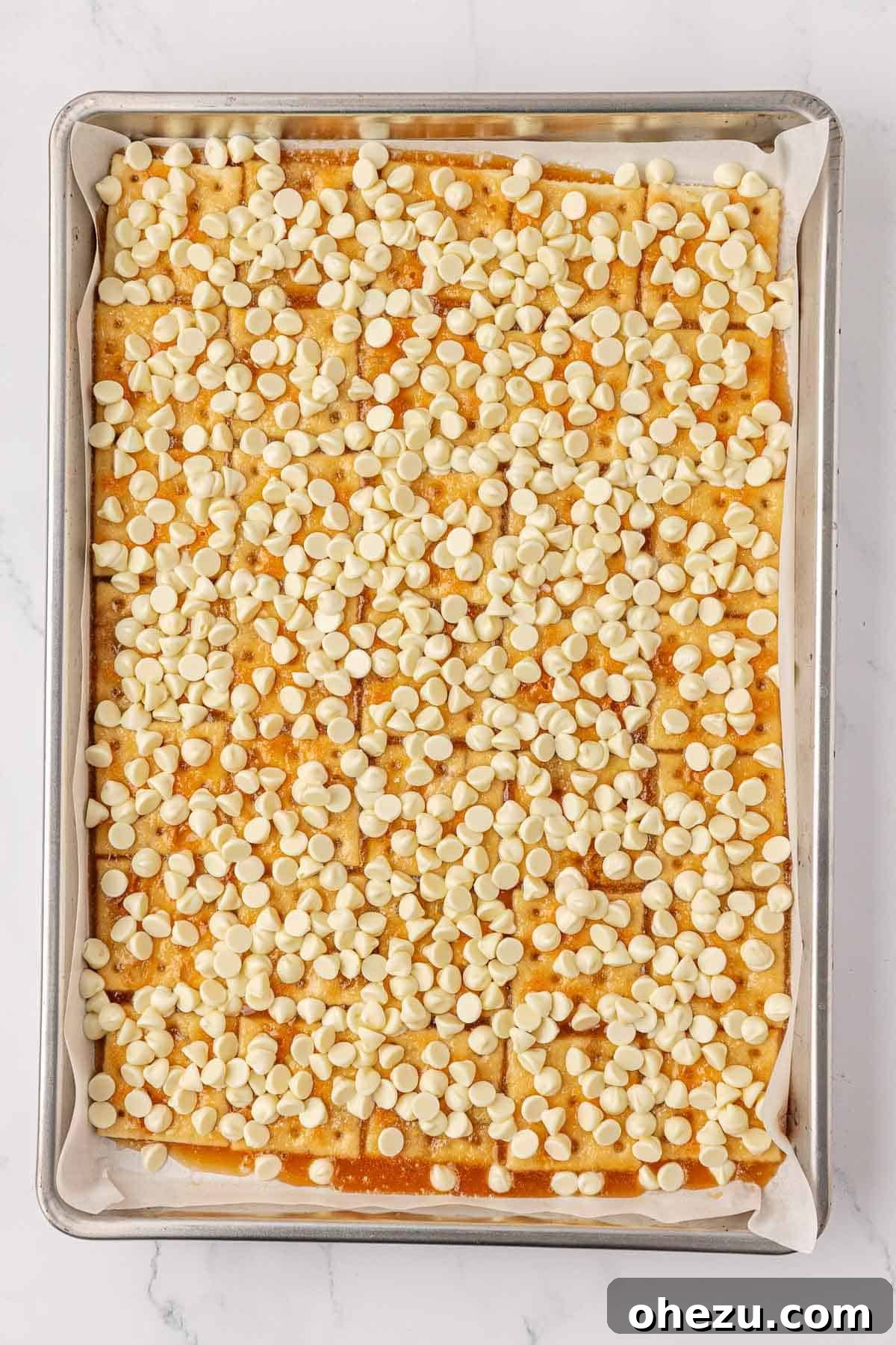 Hot, baked toffee crackers generously topped with white chocolate chips, which are beginning to melt from the residual heat