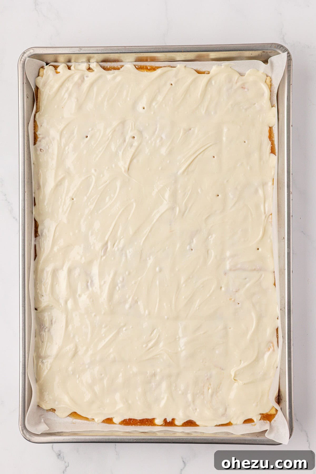 A pristine, smooth layer of melted white chocolate covering the saltine crackers, ready for toppings