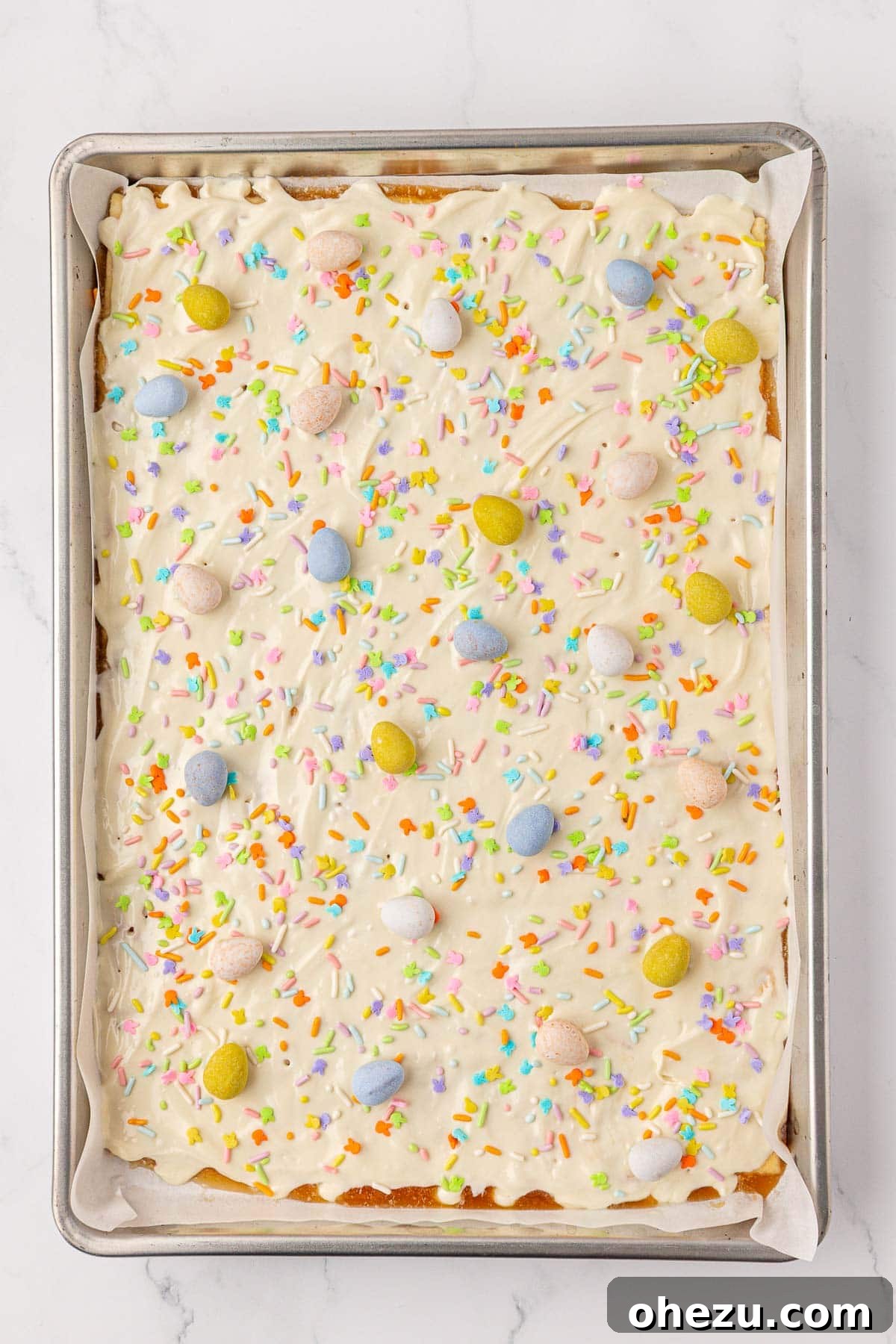 Artfully decorating the melted white chocolate with a generous scattering of Easter sprinkles and Cadbury Mini Eggs