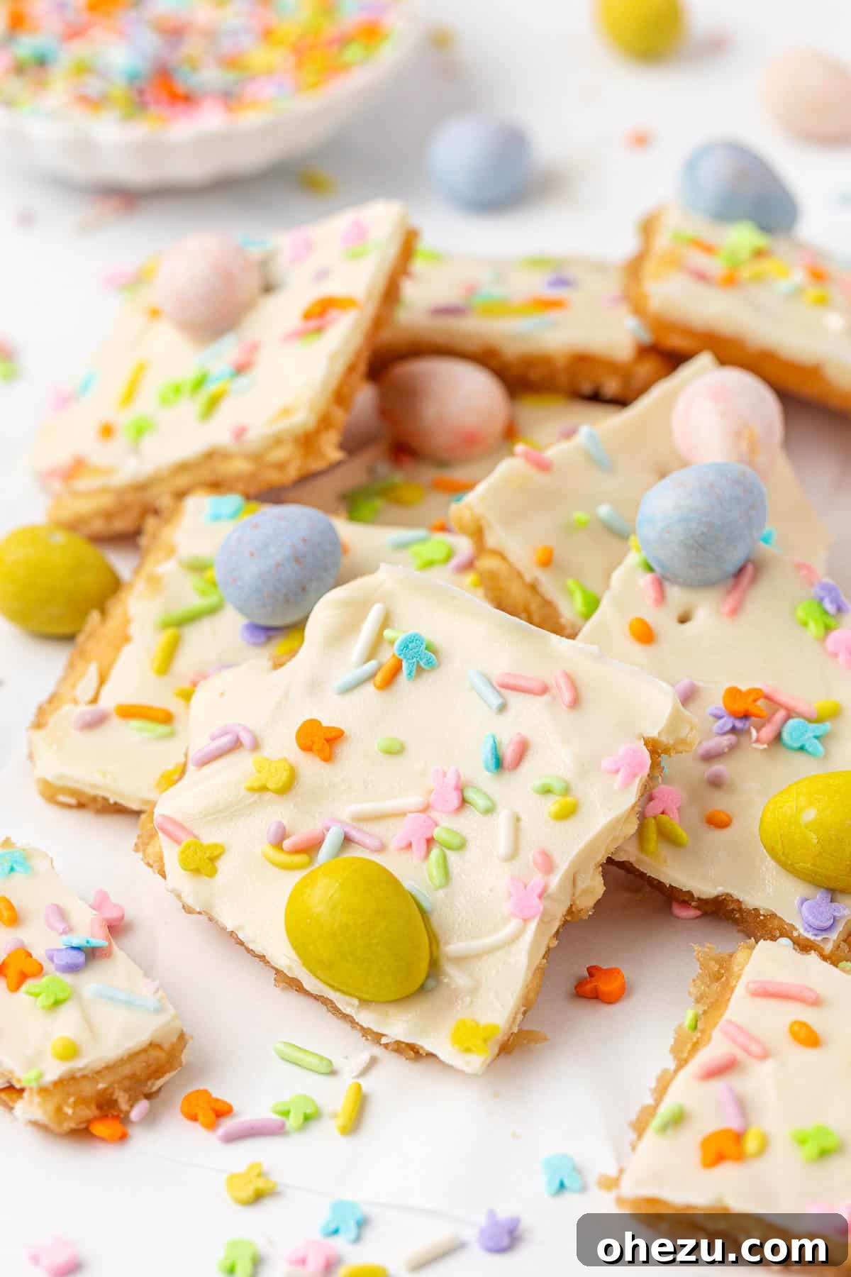 A beautiful close-up of a stack of Easter crack pieces, showing distinct layers of cracker, toffee, white chocolate, and vibrant toppings