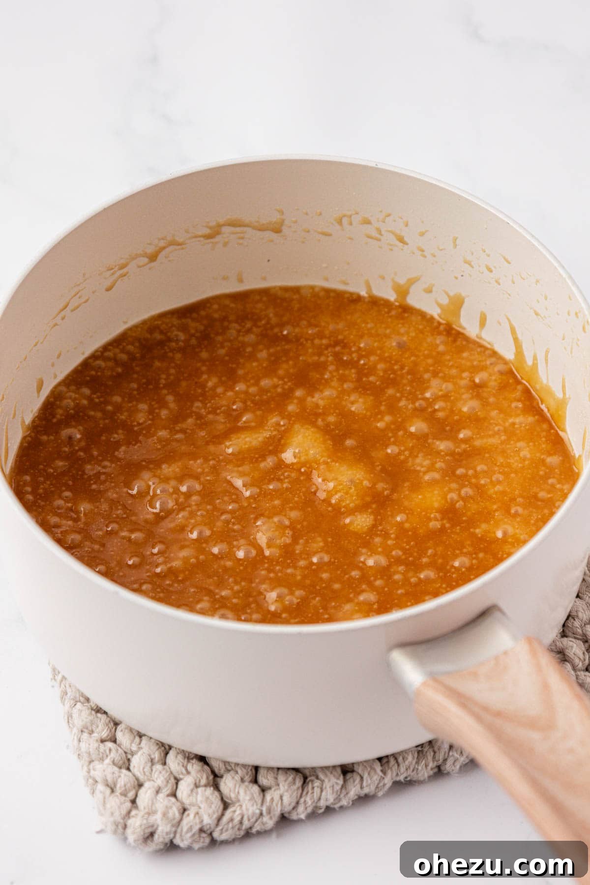 Bubbling golden toffee mixture in a saucepan, actively cooking to achieve desired thickness