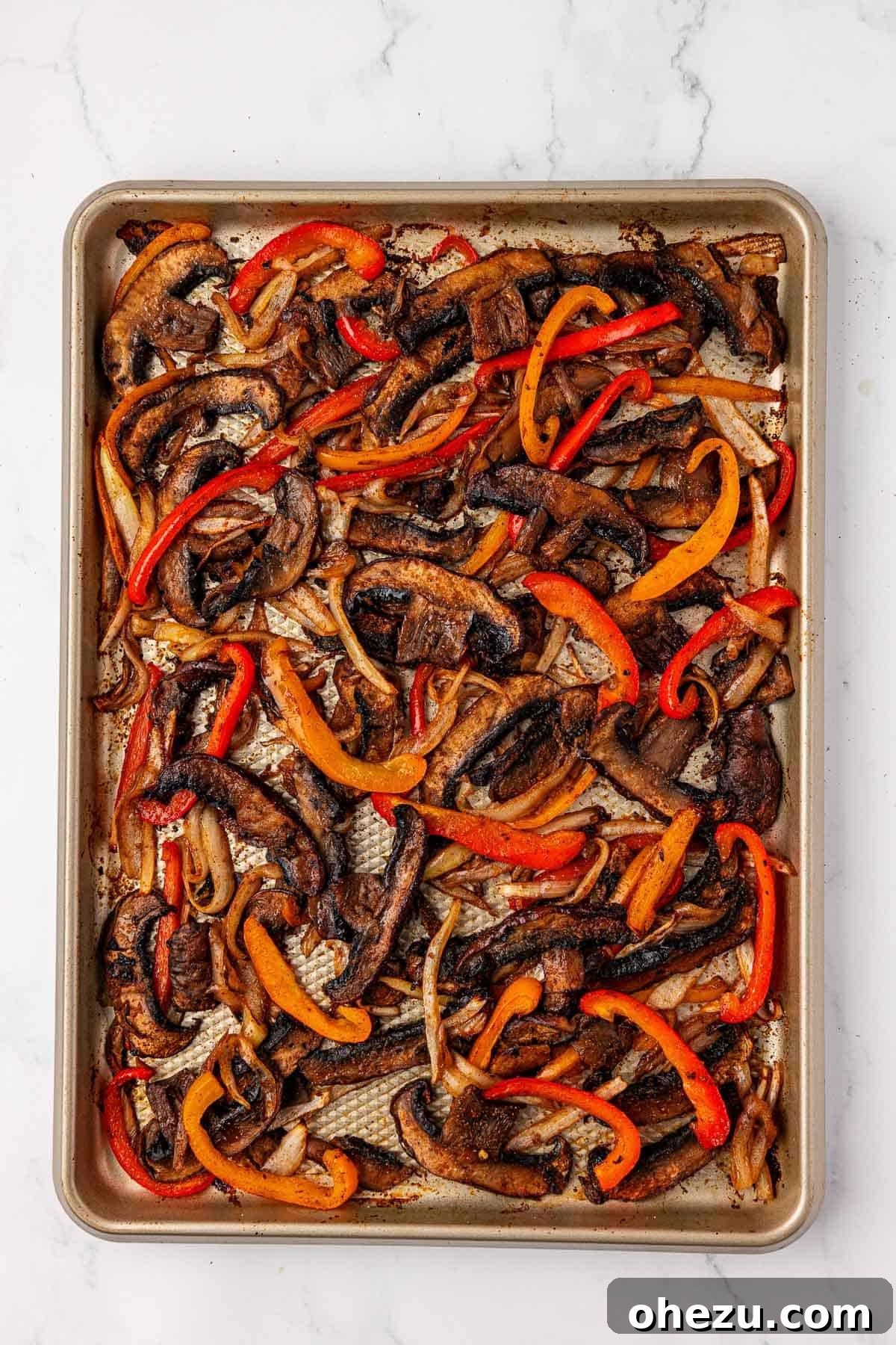Smoky Portobello Fajita Sizzle 11 Roasted portobello mushroom fajita veggies on a sheet pan after cooking, with visible caramelization