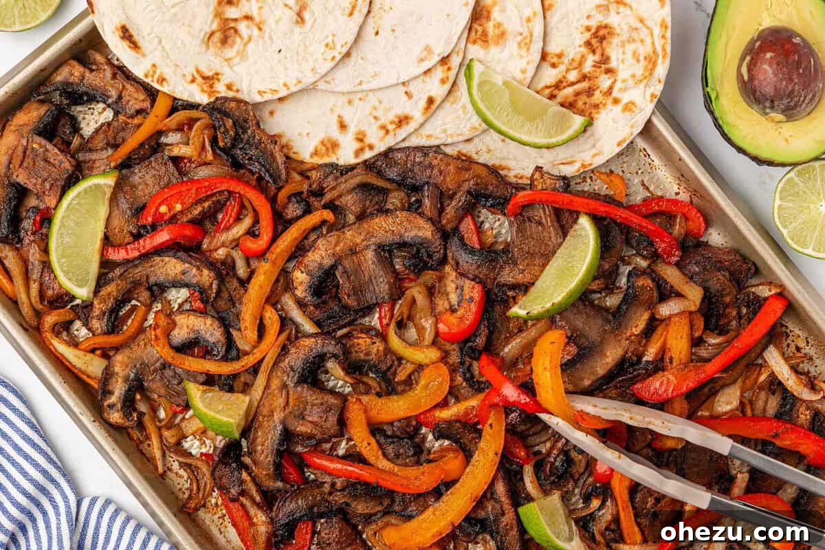 Smoky Portobello Fajita Sizzle 17 Portobello mushroom fajita veggies on a sheet pan with warm flour tortillas and fresh lime slices, ready to assemble