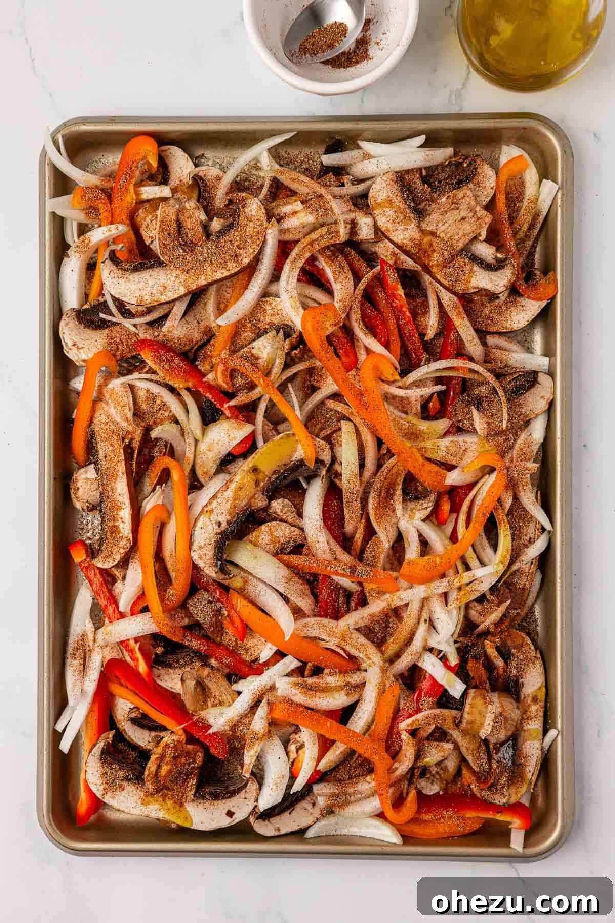 Smoky Portobello Fajita Sizzle 9 Portobello mushroom fajita veggies being tossed with olive oil and spices on a sheet pan