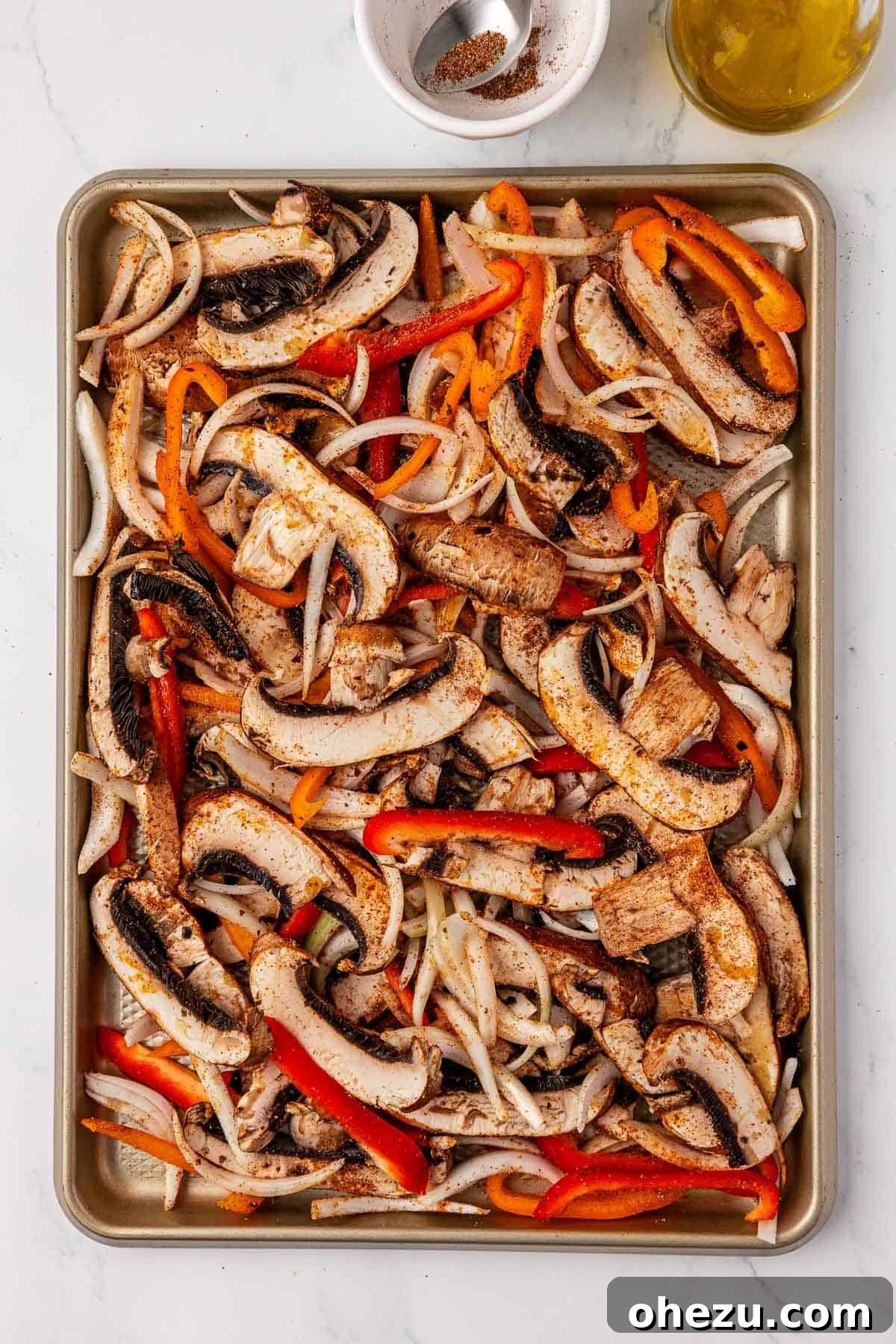 Smoky Portobello Fajita Sizzle 10 Seasoned portobello mushroom fajita veggies beautifully arranged on a sheet pan before roasting