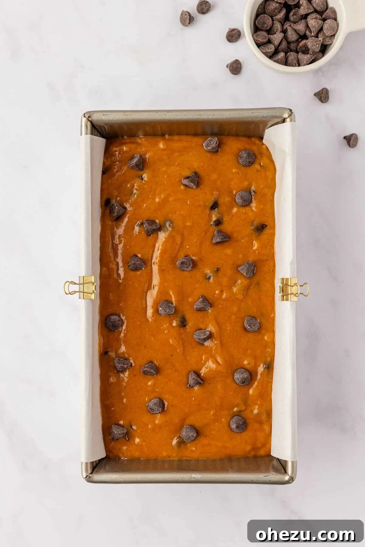 pumpkin bread batter in a loaf pan topped with chocolate chips